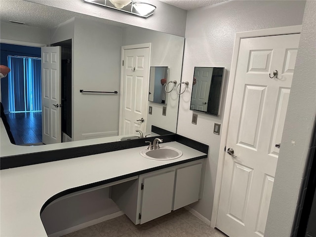 bathroom with vanity, a textured ceiling, and tile patterned floors