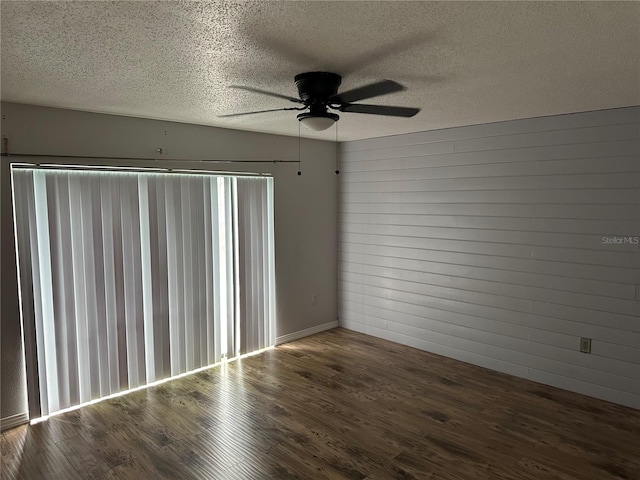 spare room featuring dark wood-type flooring, ceiling fan, and a textured ceiling