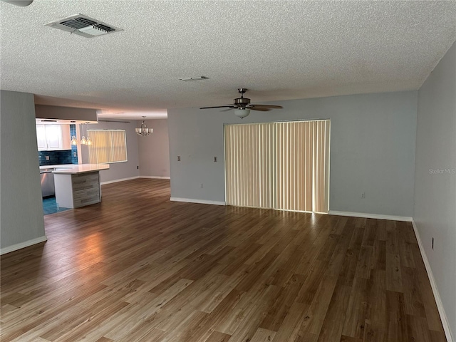 unfurnished living room featuring wood-type flooring, ceiling fan with notable chandelier, and a textured ceiling