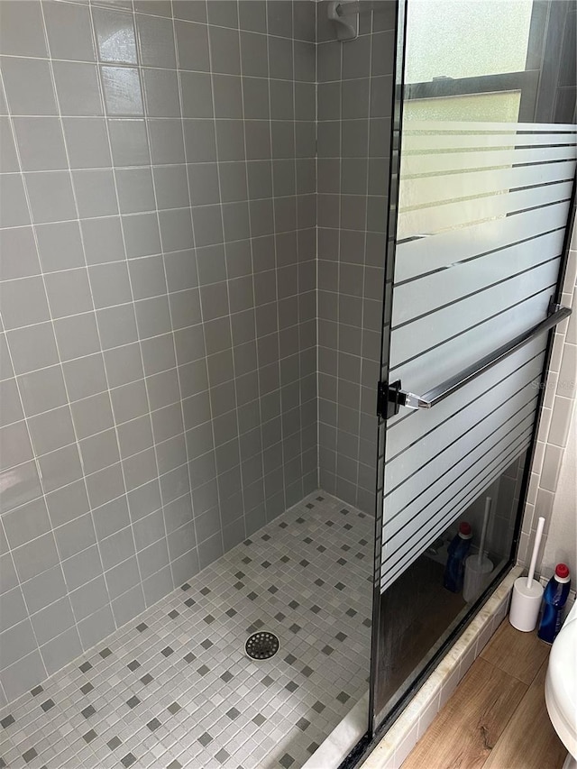 bathroom featuring wood-type flooring and tiled shower