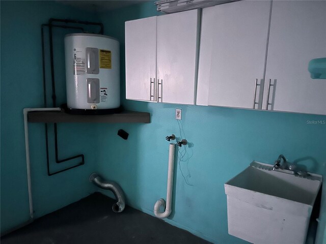 8353 Forest Oaks Blvd, Spring Hill, FL 34606 - clothes washing area featuring electric water heater and cabinet space