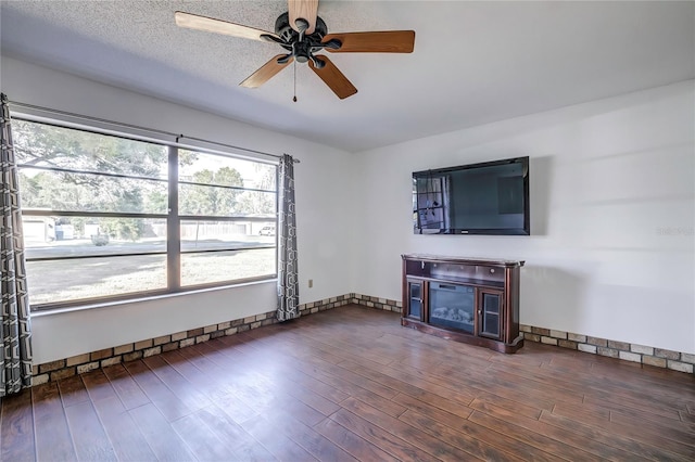 unfurnished living room featuring ceiling fan, dark hardwood / wood-style floors, and a textured ceiling