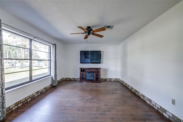 unfurnished living room with ceiling fan, a textured ceiling, and dark hardwood / wood-style floors