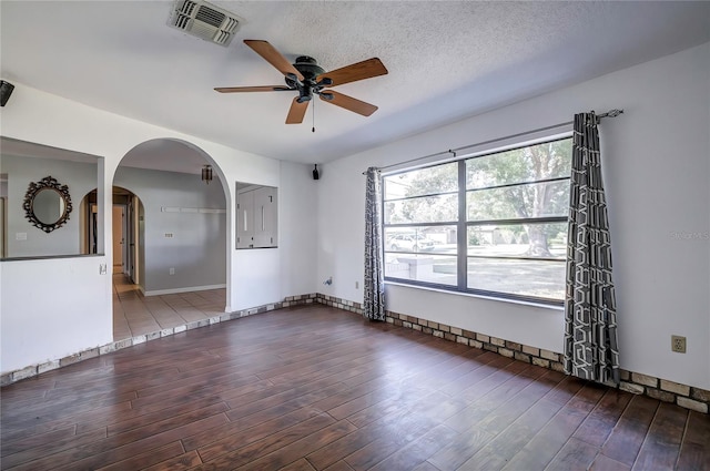 spare room with dark wood-type flooring, ceiling fan, and a textured ceiling