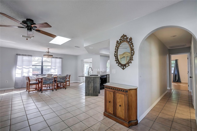 kitchen featuring hanging light fixtures, sink, an island with sink, light tile patterned flooring, and ceiling fan