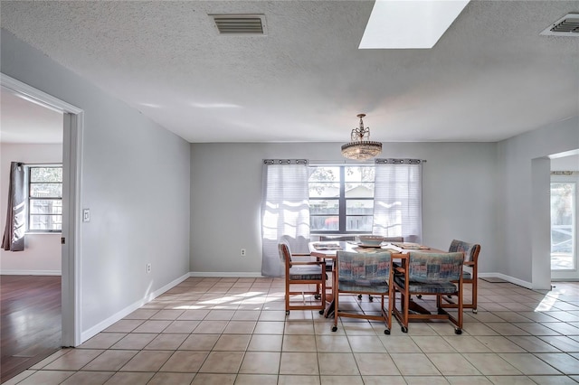 dining space with a healthy amount of sunlight, a skylight, and light tile patterned flooring