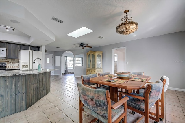 tiled dining area with ceiling fan, a textured ceiling, and a skylight