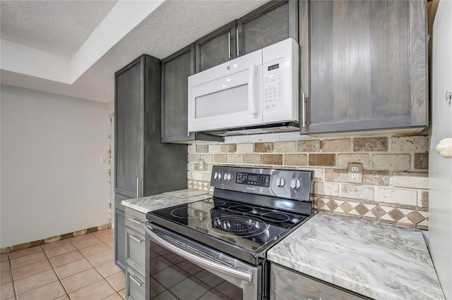 kitchen featuring dark brown cabinetry, light tile patterned flooring, a textured ceiling, stainless steel electric range oven, and decorative backsplash