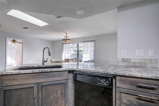 kitchen featuring light stone counters, black dishwasher, dark brown cabinetry, sink, and a skylight