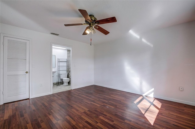 unfurnished bedroom featuring ceiling fan, ensuite bath, a closet, and dark hardwood / wood-style flooring