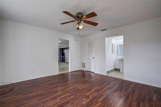 unfurnished bedroom featuring hardwood / wood-style floors, ceiling fan, ensuite bath, and a closet