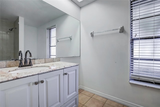 bathroom with a tile shower, vanity, a skylight, and tile patterned floors