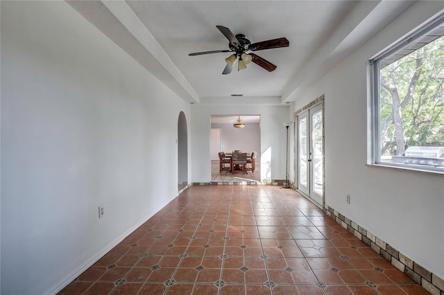 spare room featuring french doors, a wealth of natural light, dark tile patterned flooring, and ceiling fan