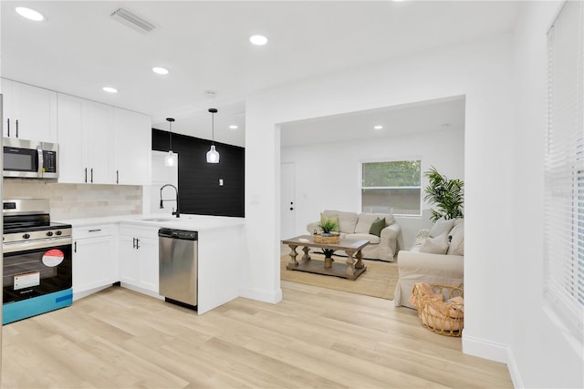 kitchen featuring light hardwood / wood-style flooring, white cabinetry, pendant lighting, and stainless steel appliances