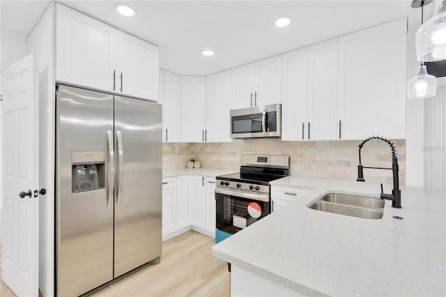 kitchen featuring white cabinetry, appliances with stainless steel finishes, sink, and decorative light fixtures