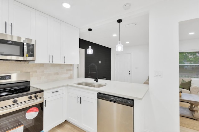 kitchen featuring white cabinets, stainless steel appliances, sink, and pendant lighting