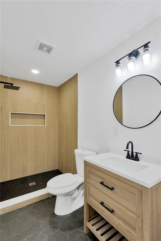 bathroom featuring a shower, tile patterned floors, toilet, and vanity