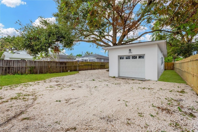 view of yard with an outbuilding, driveway, a detached garage, and a fenced backyard