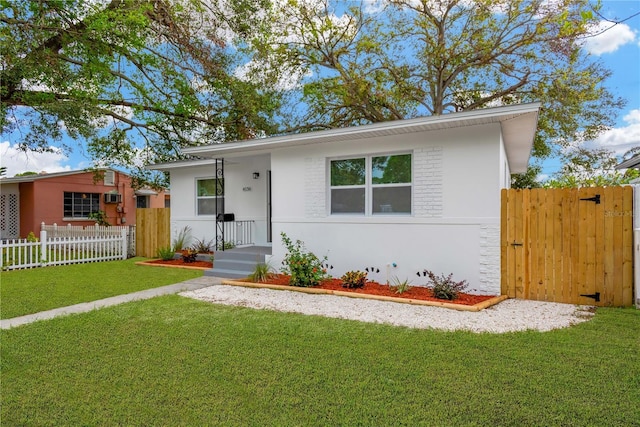 view of front facade with a front yard, fence, and stucco siding