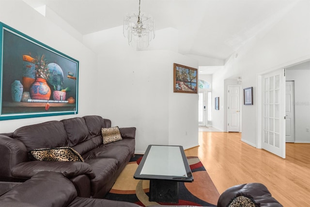 living room with lofted ceiling, hardwood / wood-style flooring, and an inviting chandelier