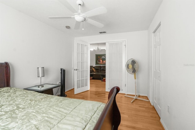 bedroom featuring a closet, wood-type flooring, and ceiling fan with notable chandelier