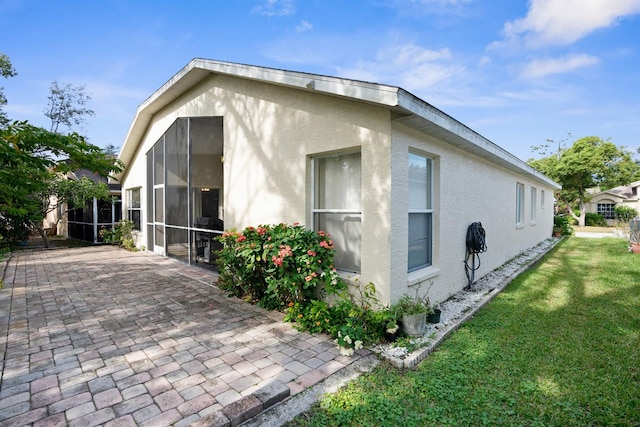 view of side of home with a sunroom, a yard, and a patio area