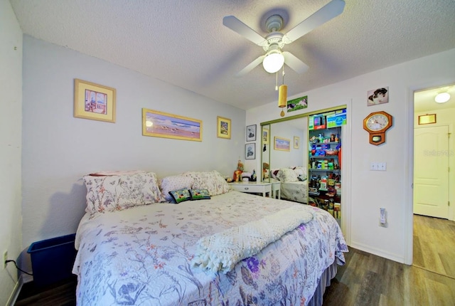 bedroom with a textured ceiling, dark wood-type flooring, ceiling fan, and a closet