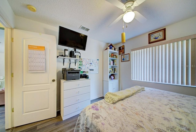 bedroom with hardwood / wood-style flooring, ceiling fan, and a textured ceiling