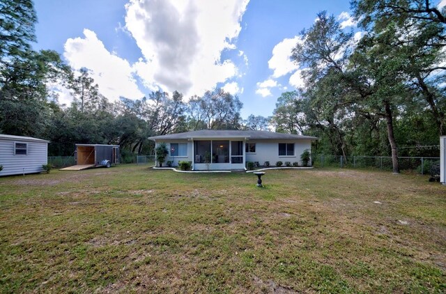 rear view of property featuring a sunroom and a yard