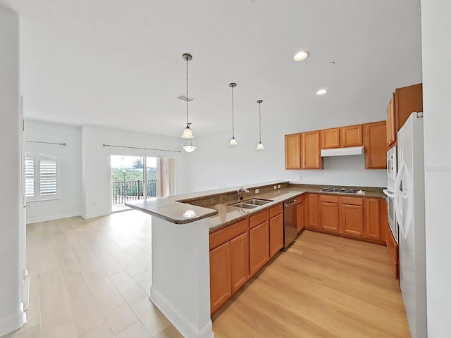 kitchen featuring stainless steel appliances, light hardwood / wood-style floors, hanging light fixtures, sink, and stone counters