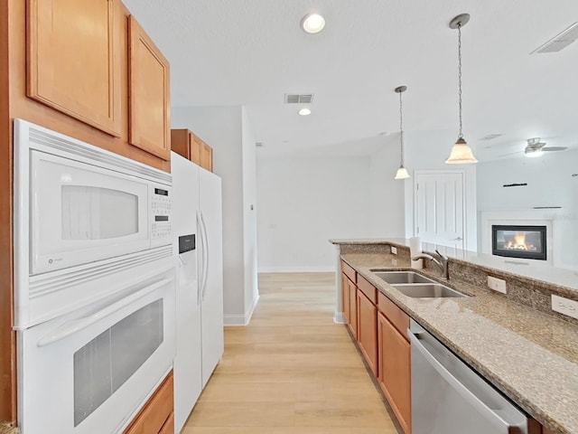 kitchen with hanging light fixtures, sink, ceiling fan, light wood-type flooring, and white appliances