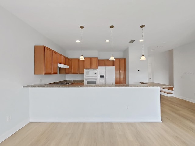 kitchen with light stone counters, kitchen peninsula, white appliances, light hardwood / wood-style flooring, and pendant lighting