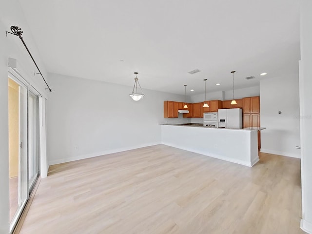 kitchen with hanging light fixtures, white appliances, light hardwood / wood-style flooring, and kitchen peninsula