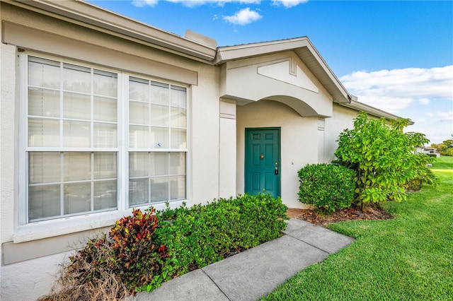 property entrance with a lawn and stucco siding