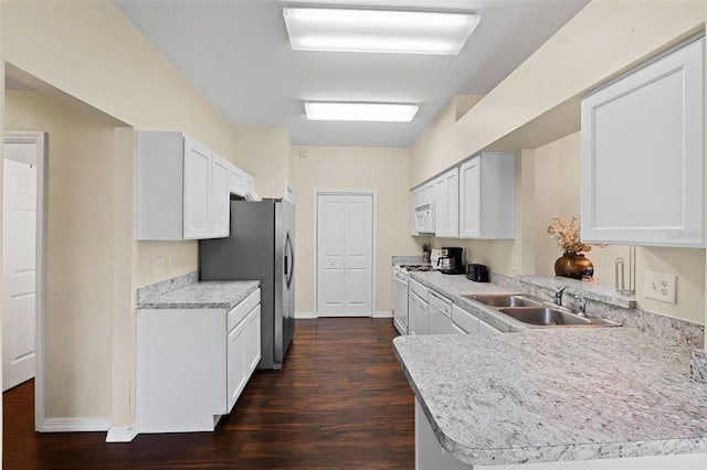 kitchen with a sink, white appliances, dark wood-type flooring, and light countertops