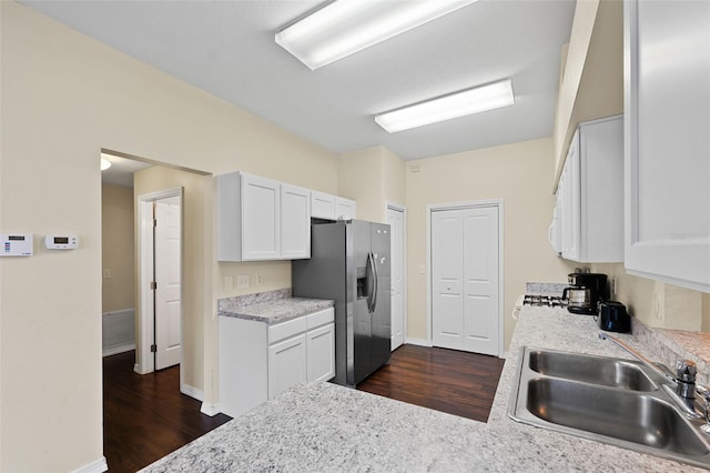 kitchen featuring stainless steel fridge, white cabinetry, and light countertops