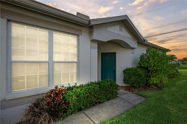 1931 Sassafras Dr, Wesley Chapel, FL 33543 - exterior entry at dusk featuring stucco siding, a garage, and a lawn