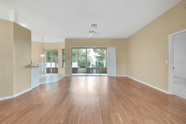 unfurnished living room featuring ceiling fan with notable chandelier, a healthy amount of sunlight, and light hardwood / wood-style flooring