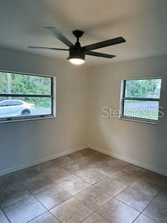 spare room with ceiling fan, plenty of natural light, and light tile patterned floors