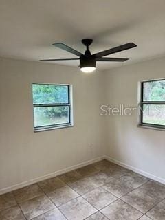 spare room with ceiling fan and light tile patterned flooring