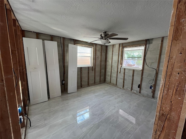 unfurnished bedroom featuring ceiling fan, a textured ceiling, and multiple windows