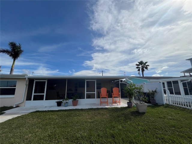 rear view of house featuring a yard, a patio area, and a sunroom