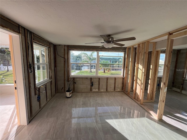 unfurnished sunroom featuring ceiling fan