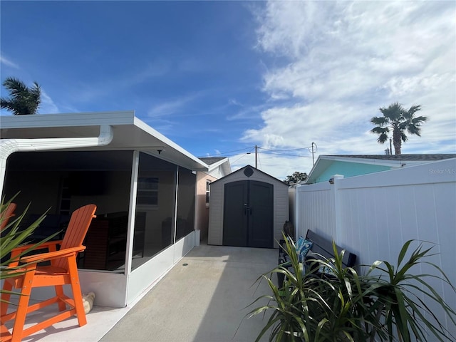 view of patio / terrace with a sunroom and a storage unit