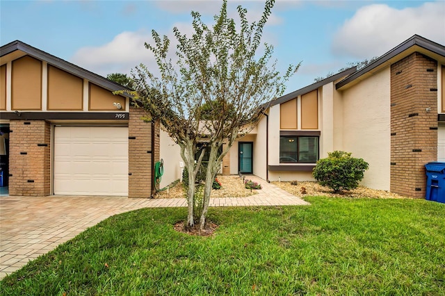 7499 Heather Walk, Weeki Wachee, FL 34613 - view of front of property with stucco siding, a front yard, an attached garage, and brick siding