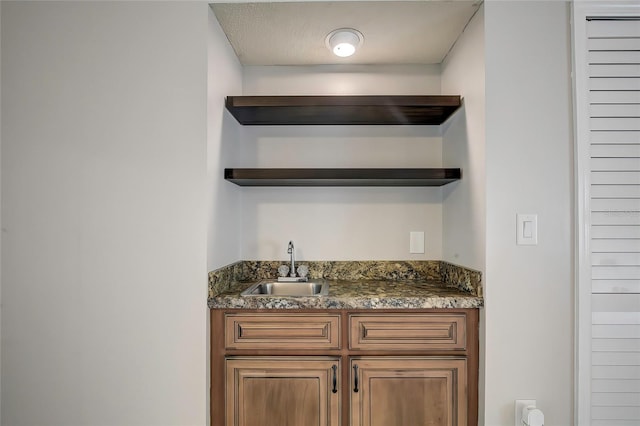 bar featuring sink and dark stone countertops