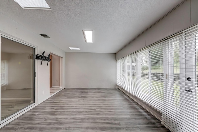 corridor featuring hardwood / wood-style floors, a textured ceiling, and a skylight