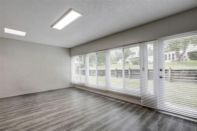 unfurnished room with a textured ceiling, hardwood / wood-style flooring, and plenty of natural light