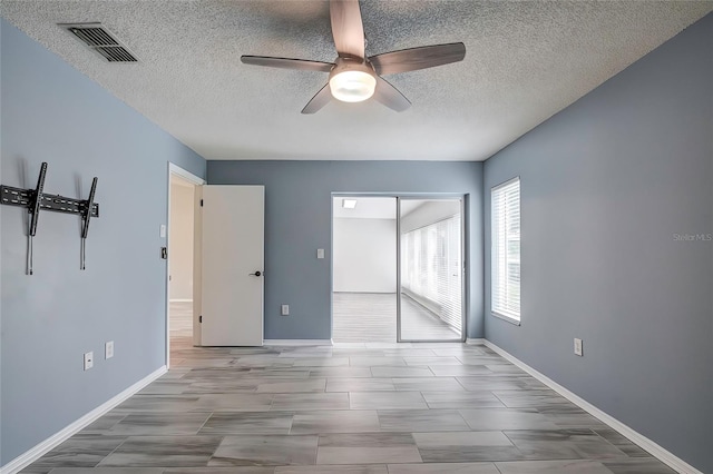 empty room with a textured ceiling and ceiling fan