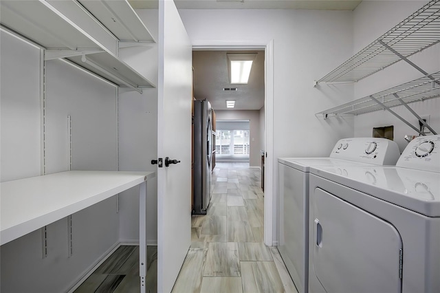 clothes washing area with light hardwood / wood-style floors and washer and dryer